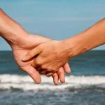 intimately holding hands at the ocean