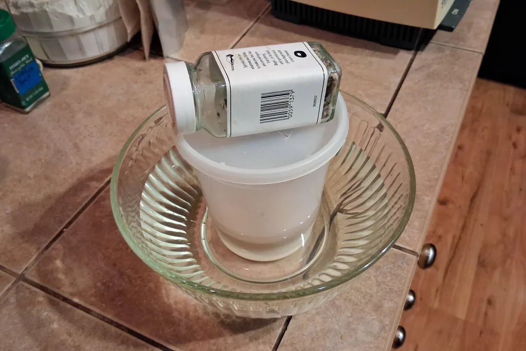 sourdough starter container in warm water bath with weight on top
