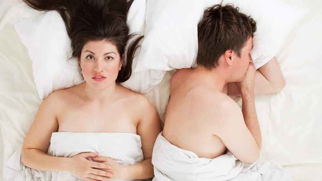 couple lying in bed, one awake and one asleep